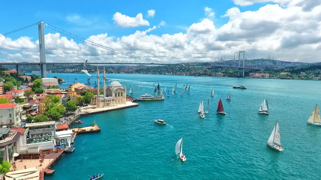 Aerial view of Ortakoy Mosque and the Bosphorus Bridge in Istanbul with sailboats on the turquoise strait
